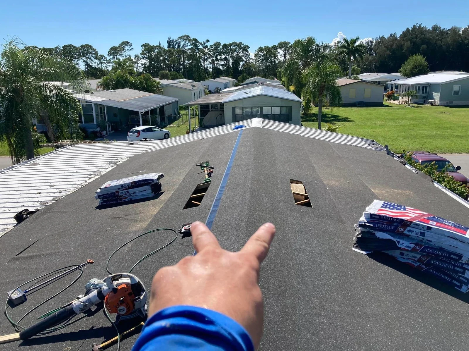 CAT 6 roofer pointing out work on a shingle roof replacement
